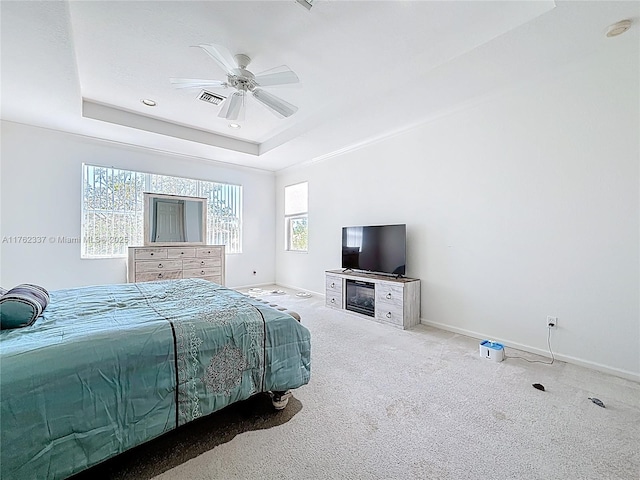 carpeted bedroom with baseboards, a tray ceiling, multiple windows, and visible vents