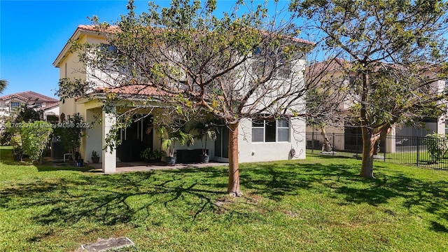 back of property with stucco siding, a patio, a yard, and fence