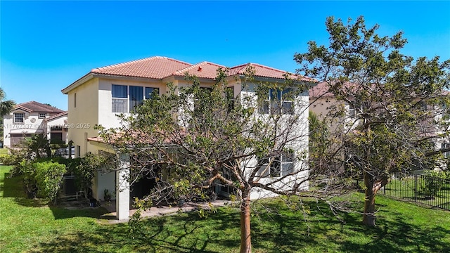 view of front of home with stucco siding, fence, a front yard, and a tiled roof