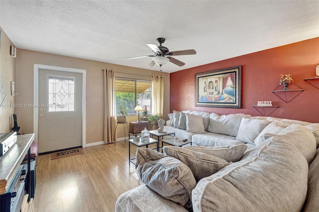 living room with a textured ceiling, baseboards, light wood finished floors, and ceiling fan