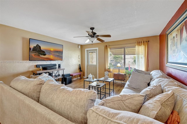 living area with light wood finished floors, ceiling fan, and a textured wall