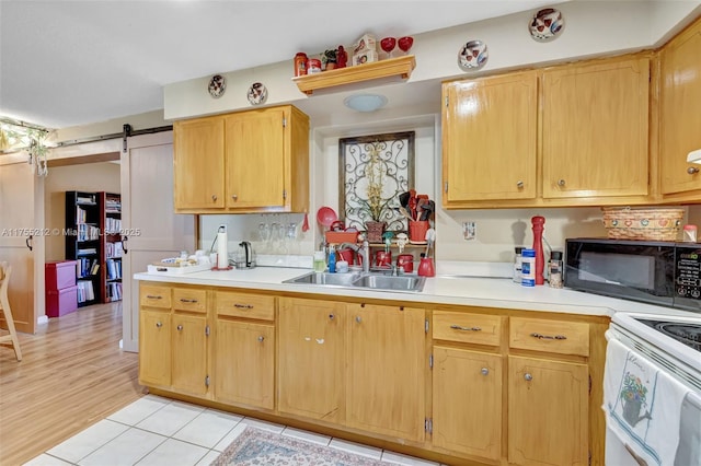 kitchen featuring white range with electric cooktop, a sink, a barn door, black microwave, and light countertops