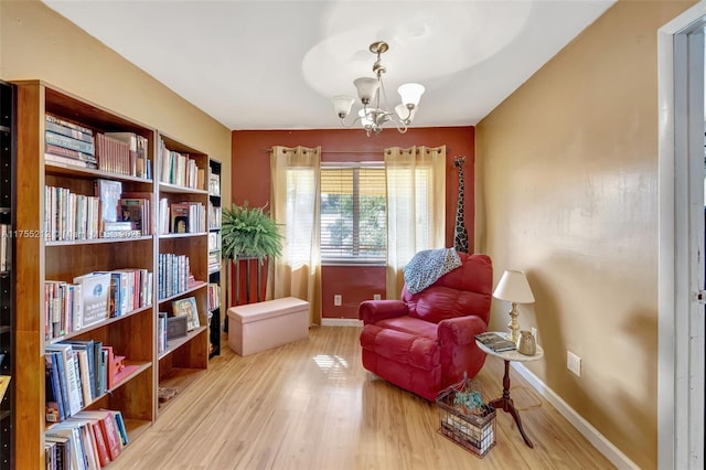 living area featuring baseboards, wood finished floors, and a chandelier