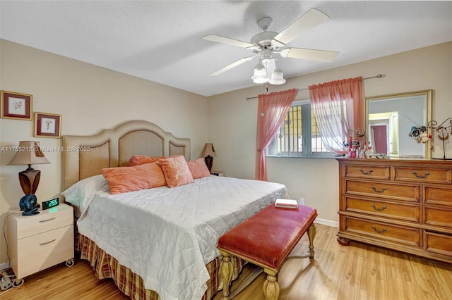 bedroom featuring baseboards, a textured ceiling, light wood-style floors, and a ceiling fan