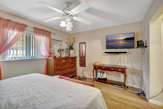 bedroom featuring baseboards, wood finished floors, and a ceiling fan