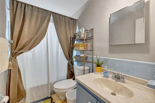 bathroom featuring a wainscoted wall, toilet, tile walls, and vanity