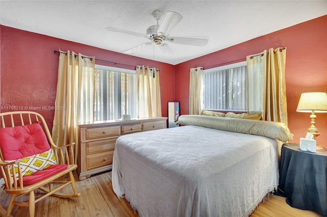 bedroom featuring multiple windows, a ceiling fan, and light wood finished floors