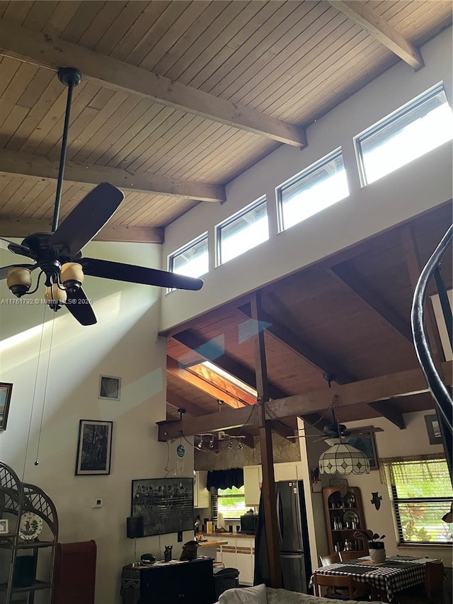 living room featuring beam ceiling, plenty of natural light, a ceiling fan, and visible vents