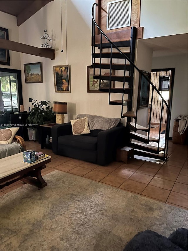 living area with stairs, a high ceiling, visible vents, and tile patterned flooring