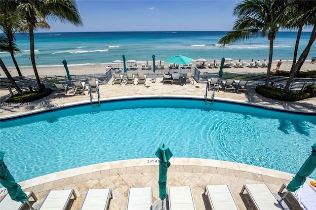 community pool featuring a water view, a patio, and a view of the beach