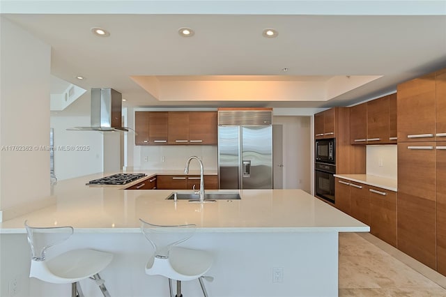 kitchen featuring a sink, black appliances, exhaust hood, modern cabinets, and brown cabinets