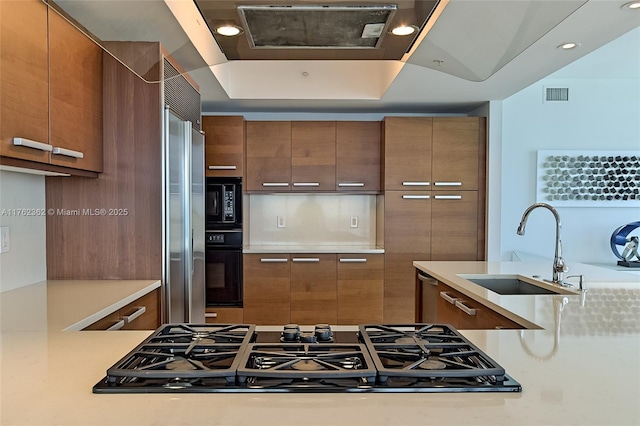 kitchen with a sink, modern cabinets, black appliances, and light countertops