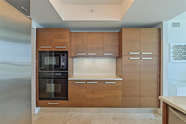 kitchen with visible vents, modern cabinets, black appliances, brown cabinetry, and light countertops