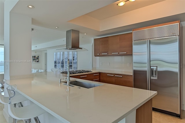 kitchen featuring island exhaust hood, stainless steel built in fridge, a peninsula, and modern cabinets