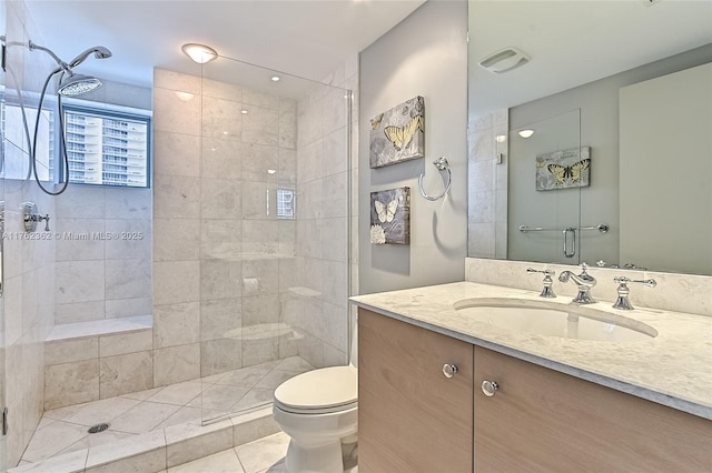 bathroom with visible vents, toilet, tiled shower, and vanity