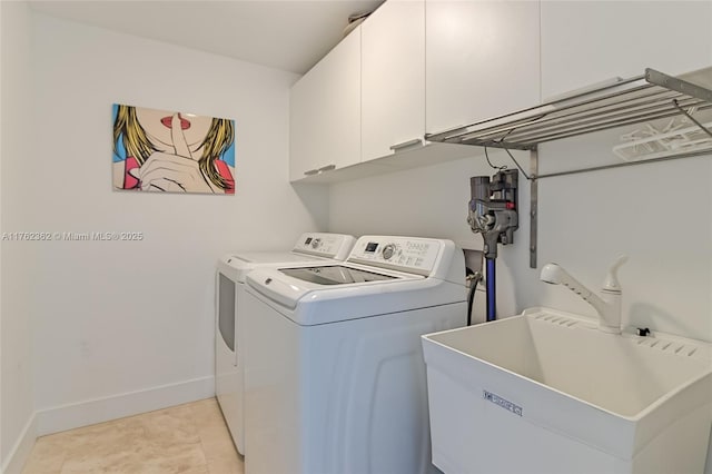 washroom with light tile patterned floors, baseboards, cabinet space, a sink, and washer and dryer