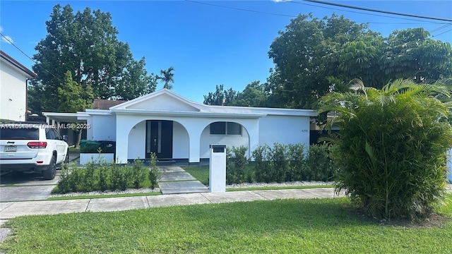 view of front of home featuring covered porch, stucco siding, a front lawn, and an attached carport