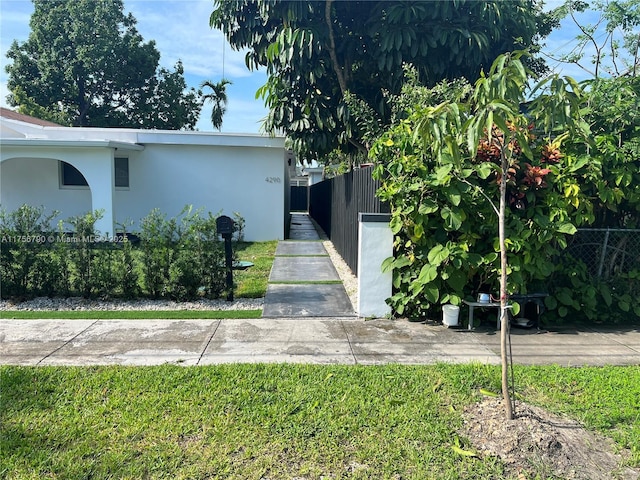 view of front facade featuring stucco siding, a front lawn, and fence