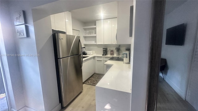 kitchen with modern cabinets, open shelves, freestanding refrigerator, white cabinets, and light countertops