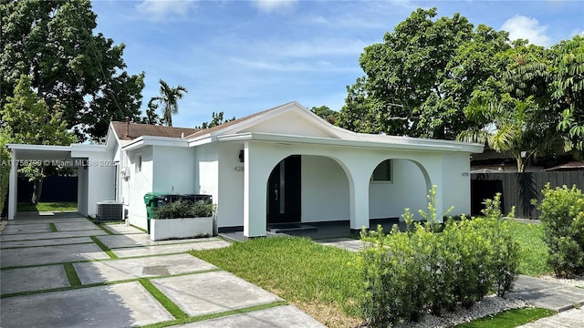 view of front of property featuring stucco siding, central air condition unit, covered porch, and fence