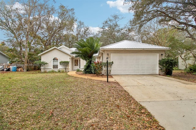 ranch-style house featuring a front yard, driveway, an attached garage, stucco siding, and metal roof