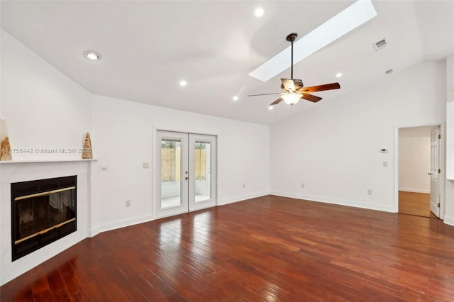 unfurnished living room with visible vents, hardwood / wood-style flooring, a glass covered fireplace, french doors, and vaulted ceiling with skylight