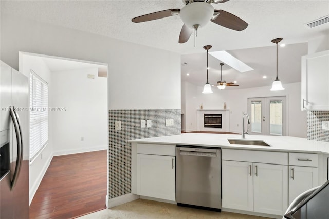 kitchen featuring visible vents, a peninsula, a sink, stainless steel appliances, and light countertops