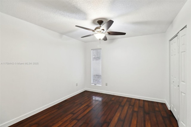 unfurnished bedroom featuring a closet, baseboards, a textured ceiling, and dark wood-style flooring