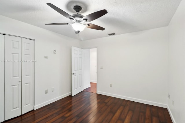 unfurnished bedroom with hardwood / wood-style floors, baseboards, visible vents, and a textured ceiling