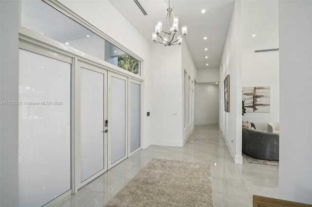 hallway featuring a high ceiling, recessed lighting, baseboards, and a chandelier