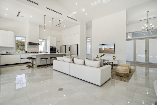 living area featuring a chandelier, visible vents, marble finish floor, and a high ceiling