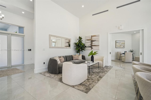 living room with visible vents, marble finish floor, a high ceiling, and baseboards