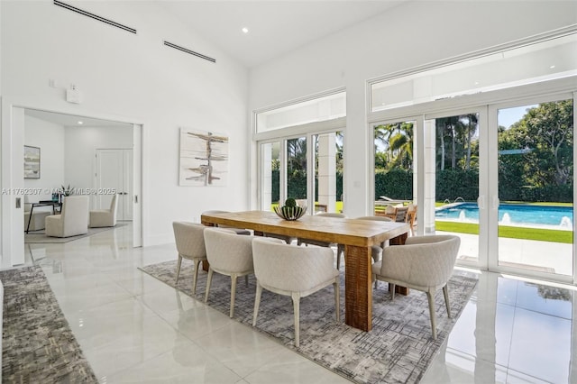 dining space with a wealth of natural light, high vaulted ceiling, marble finish floor, and recessed lighting