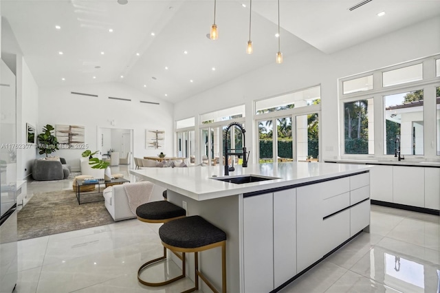 kitchen with high vaulted ceiling, modern cabinets, a sink, open floor plan, and white cabinetry