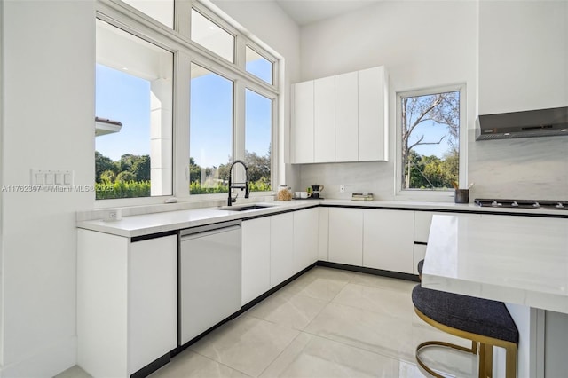 kitchen featuring gas stovetop, white dishwasher, a sink, light countertops, and white cabinets