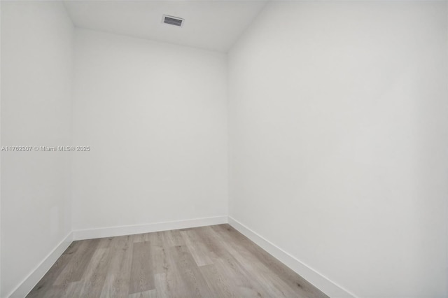 empty room with baseboards, visible vents, and light wood-type flooring