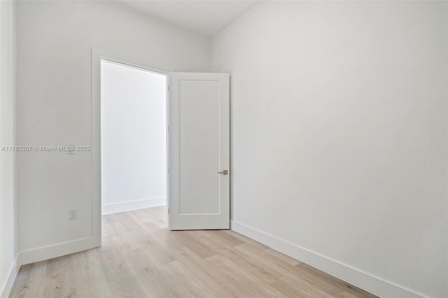 spare room with baseboards and light wood-style floors