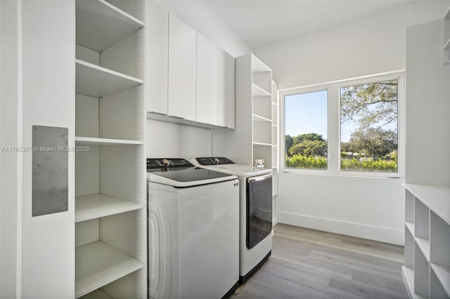 laundry area featuring cabinet space, light wood-style floors, independent washer and dryer, and baseboards