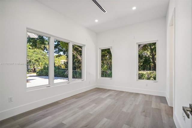 unfurnished room featuring a wealth of natural light, recessed lighting, light wood-type flooring, and baseboards