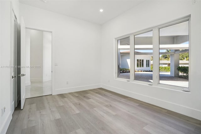 empty room featuring recessed lighting, baseboards, and light wood finished floors