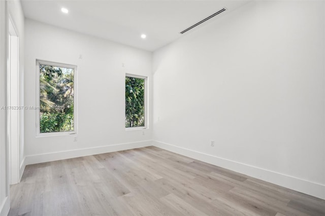 empty room with light wood-type flooring, visible vents, baseboards, and recessed lighting