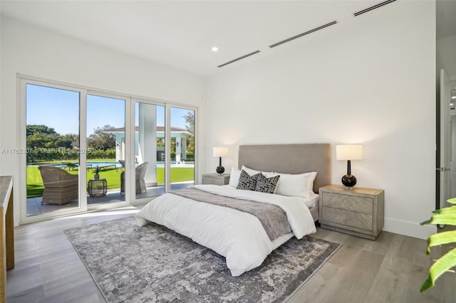 bedroom with recessed lighting, baseboards, wood finished floors, and access to exterior