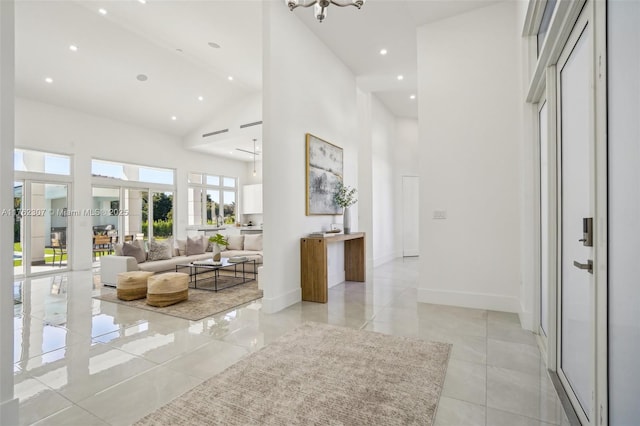 corridor featuring recessed lighting, baseboards, a high ceiling, and light tile patterned floors