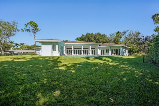 rear view of house featuring a yard and stucco siding