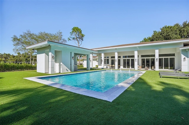 rear view of house with a lawn, an outdoor pool, and stucco siding