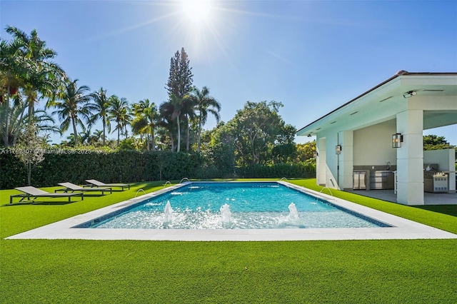 view of pool with a yard, a fenced in pool, and an outdoor kitchen