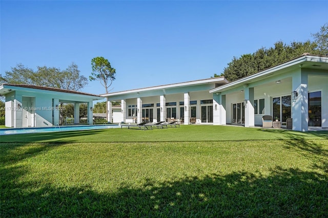 back of house featuring stucco siding, an outdoor pool, and a yard