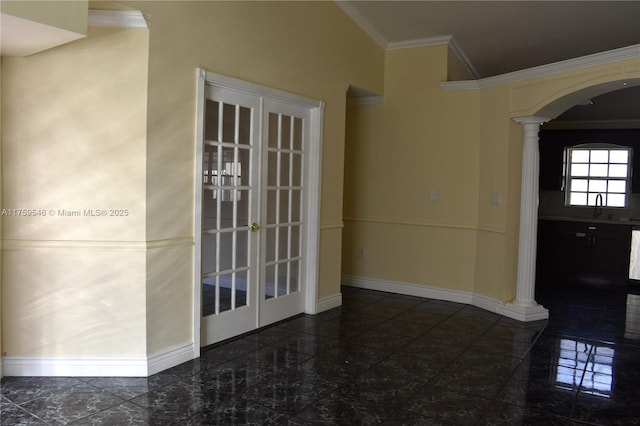 spare room featuring baseboards, granite finish floor, decorative columns, arched walkways, and ornamental molding