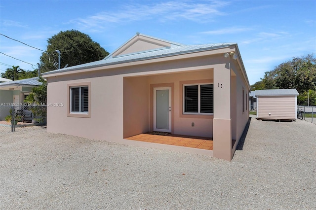 view of front of house featuring an outbuilding, metal roof, and stucco siding