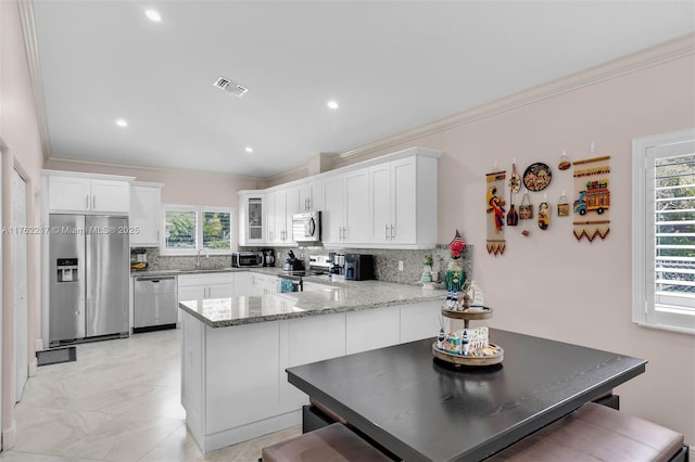 kitchen featuring visible vents, backsplash, crown molding, a peninsula, and stainless steel appliances